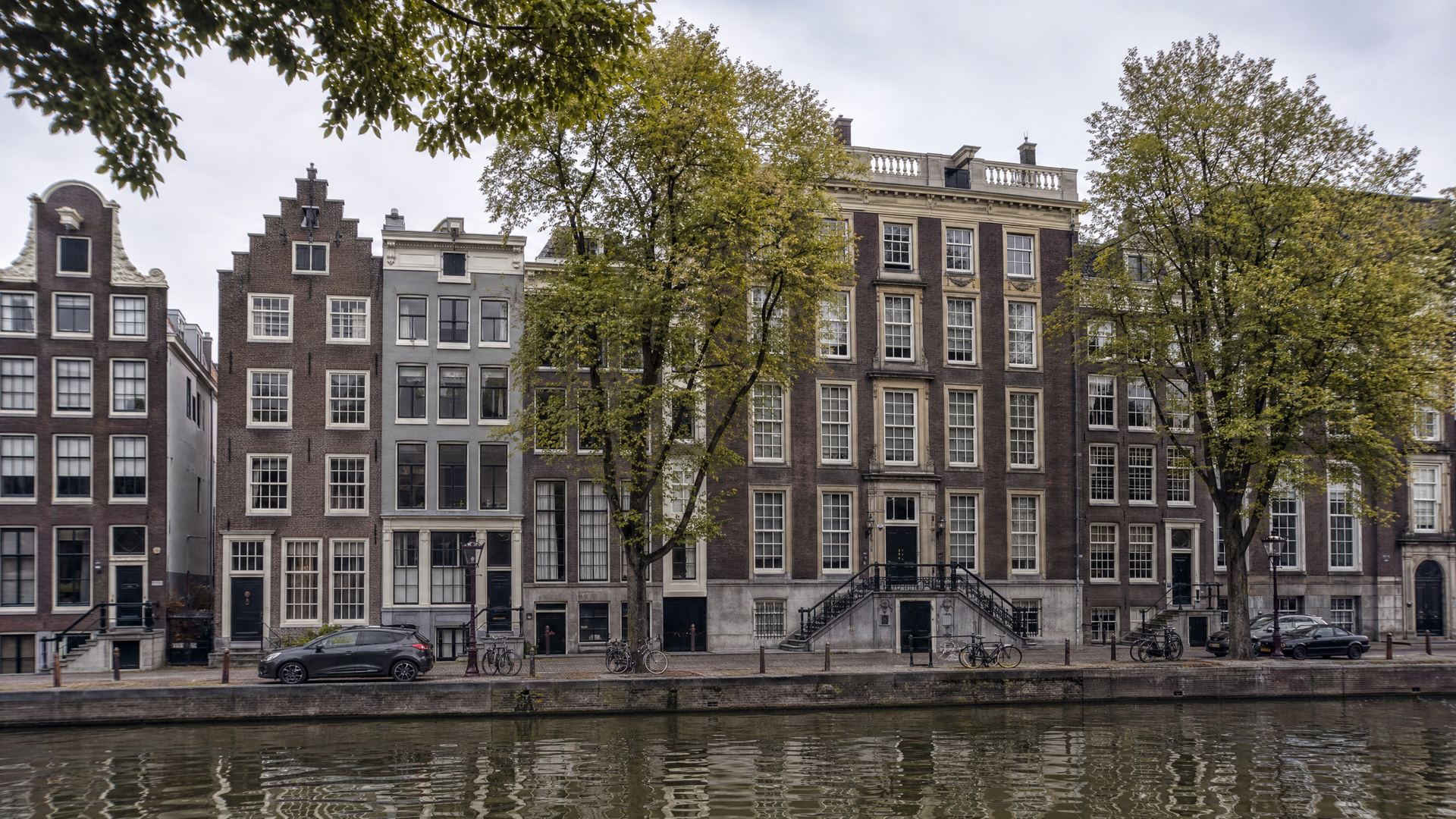 Sfeerbeeld van een rij grachtenpanden aan het water op een bewolkte dag